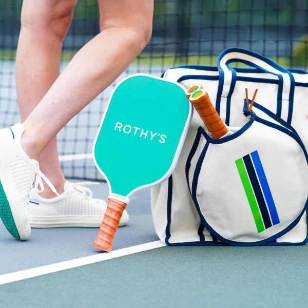 Rothy's custom pickleball paddle laying beside a pickleball bag