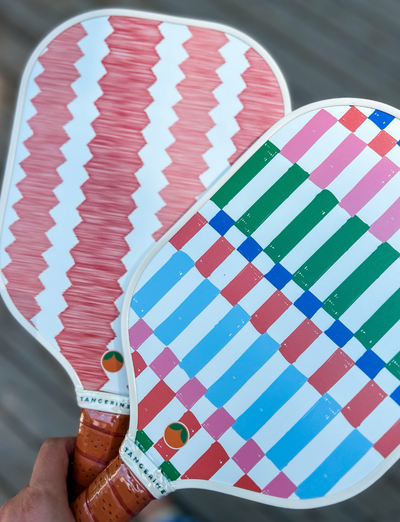 Person holding two colorful and cute pickleball paddles