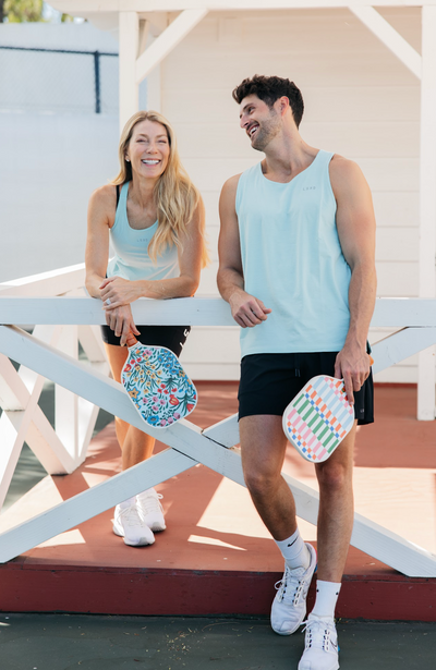 Two pickleball players hanging out with colorful paddles. 