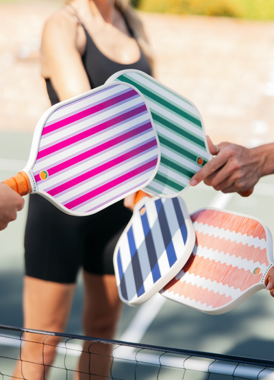 Tapping colorful pickleball paddles together. 