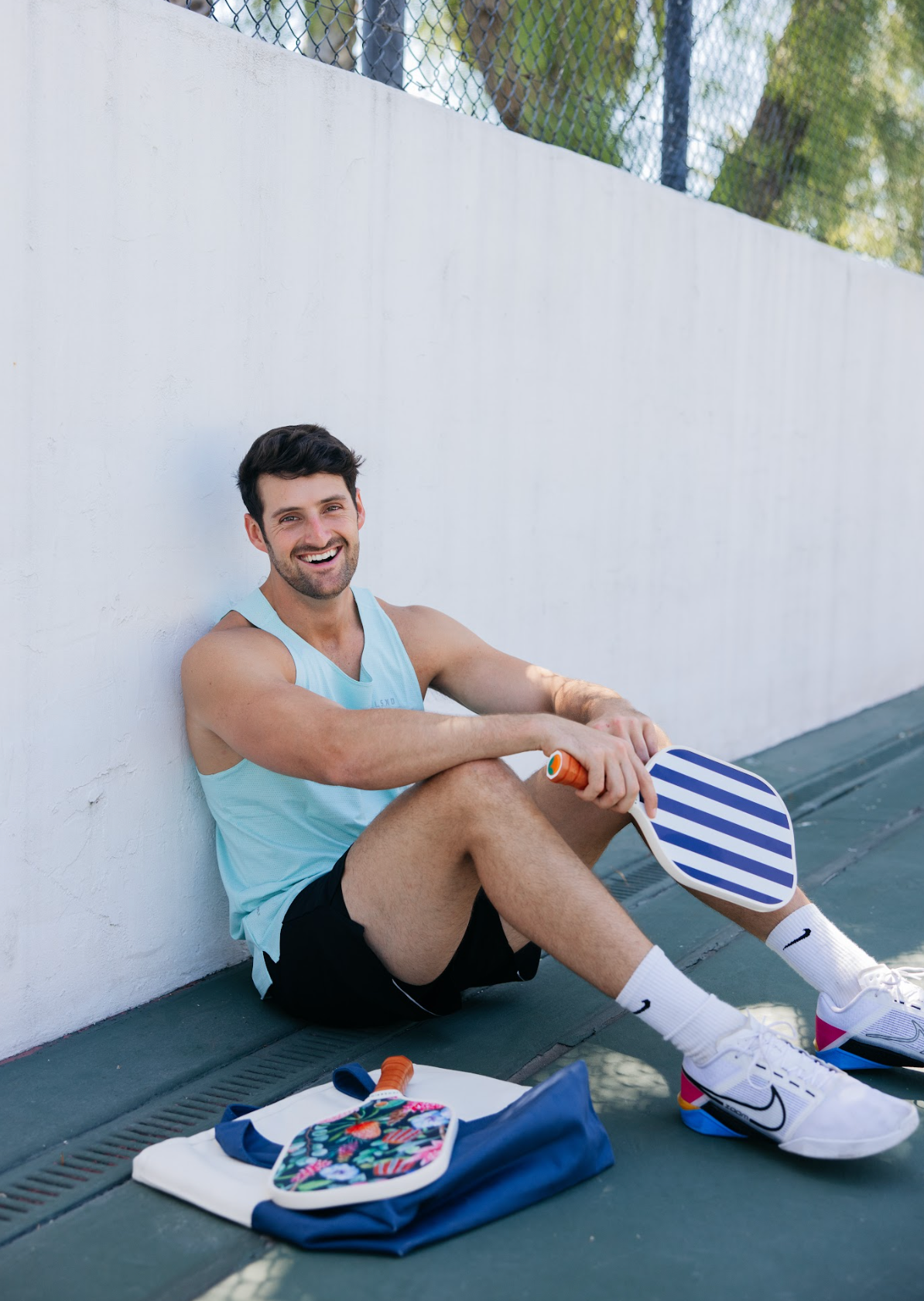 Man holding Santorini blue and white stripe pickleball paddle. 