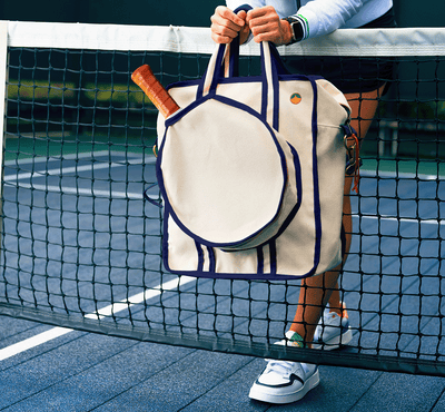 Woman holding navy blue pickleball bag with paddle. 